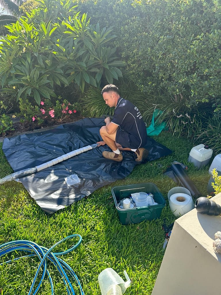 A professional plumber in Nowra performing pipe relining using no-dig technology to repair underground pipes.